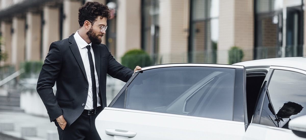 Serious businessman with documents driving on car back seat